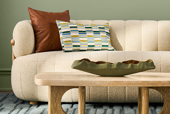 A living room featuring a cozy, cream-colored sofa & a stylish wooden coffee table.