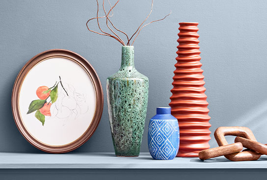 Stylish vases, faux florals, and gold candlesticks on a decorative book.